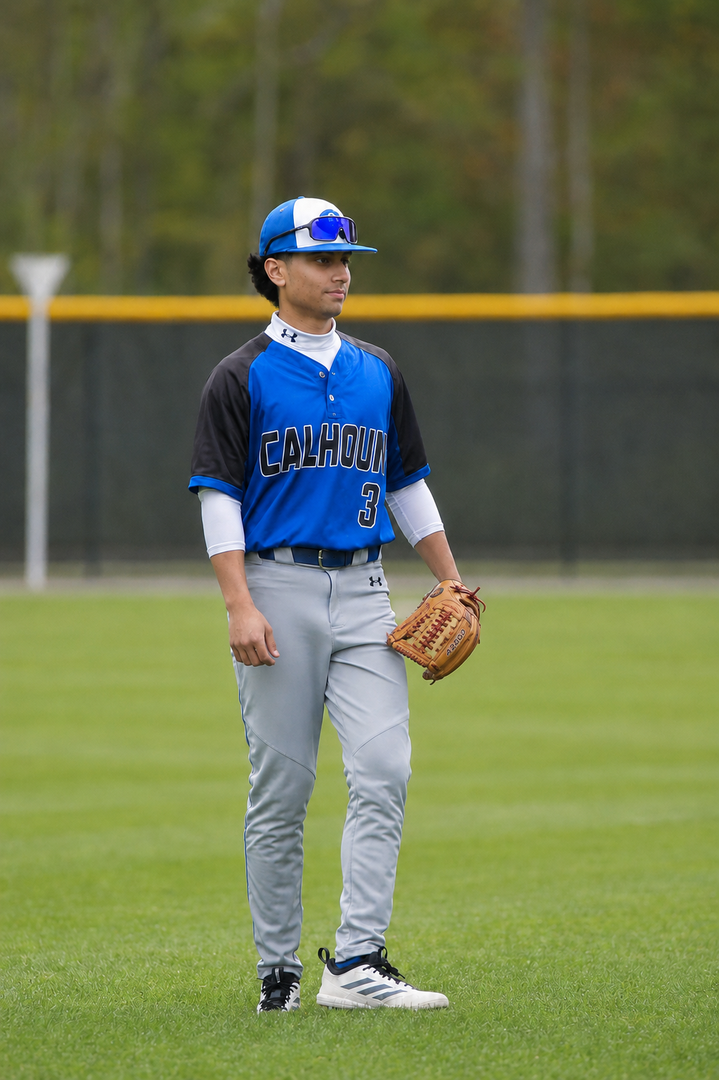 Akif Khan in a Calhoun baseball uniform standing in the outfield with his glove